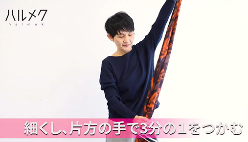 左手はストールの端をつかみながら、右手でストールを細くしごきながら3分の1の長さでつかみます